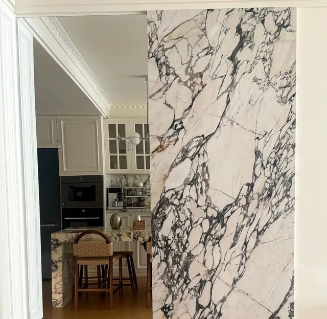 White marble-look porcelain slab used as an interior feature wall beside a kitchen