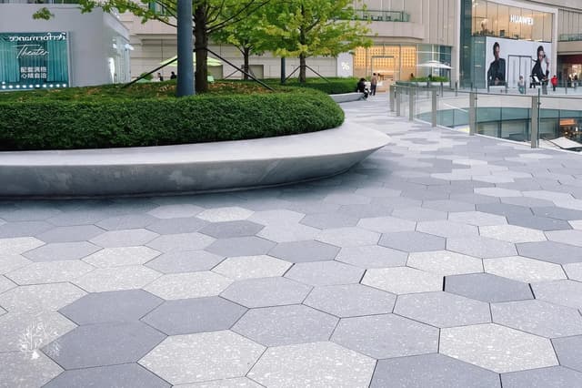 Grey hexagonal outdoor paving tiles across a landscaped commercial terrace