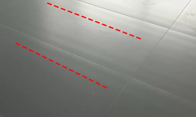 Side lighting and red guide lines revealing surface flatness across large format floor tiles