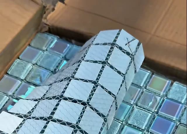 Back of a mesh-mounted mosaic tile sheet showing backing coverage and joint spacing
