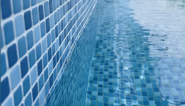 Blue mosaic tile detail at the waterline of a completed resort swimming pool