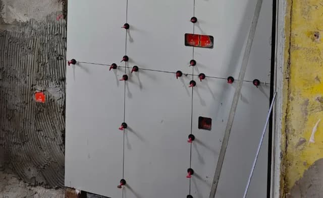 Large wall tiles being installed with adhesive coverage and levelling clips
