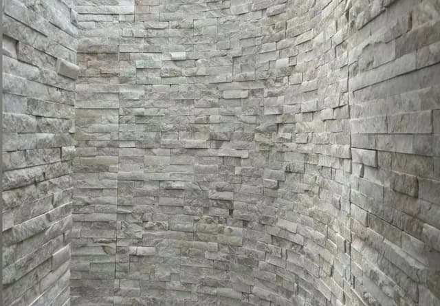 Grey split-face wall cladding installed across a curved architectural wall