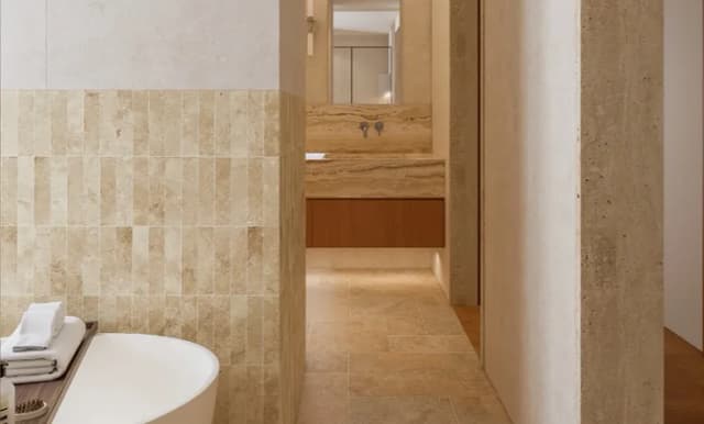 Warm beige wall and floor tiles surrounding a modern bathroom and vanity